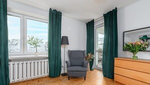 Ett rum med ett element, en grå fåtölj, en byrå i trä och en golvlampa.