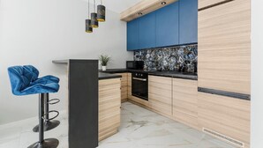 Une cuisine moderne avec des meubles en bois, un pare-feu bleu et un plan de travail noir.