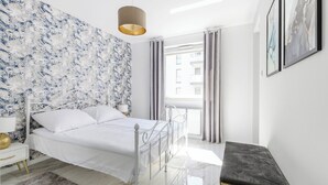 Une chambre à coucher moderne, avec un lit, une table de chevet, une lampe et une vue sur l’extérieur.