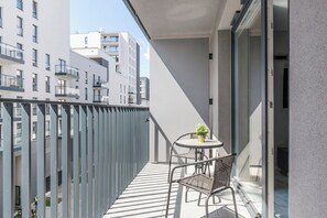 A balcony with a table and chairs, a potted plant, and a view of adjacent buildings. - Luxurious Flat with magnificent sea view (Łódź)