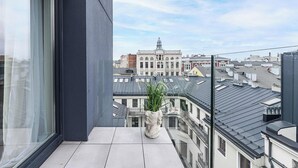 A balcony with a potted plant, a view of a historic building, and a clear sky. - Home near Piotrkowska Street (Łódź)