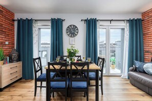 A dining area with a wooden table, blue upholstered chairs, and a wall clock. - Home near Piotrkowska Street (Łódź)