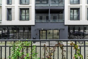 Ein modernes Gebäude mit Glasfassade, einem zentralen Eingang und einem Balkon.