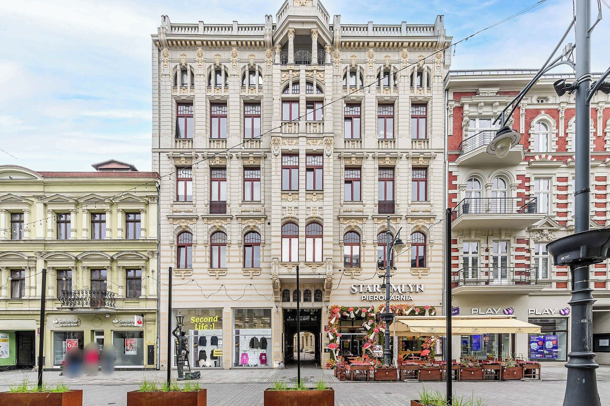 A historic building with ornate architecture, a storefront with a floral display, and a pedestrian area with planters.