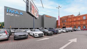 A parking lot with multiple cars, a cinema building with 'IMAX' signage, and a red brick building labeled 'CINEMA CITY'. - Magnificent seafront duplex in Porspoder (Łódź)