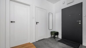 A hallway with three doors, one of which is black, and a small green stool. - Magnificent seafront duplex in Porspoder (Łódź)