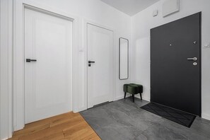Ein Flur mit drei Türen, davon eine schwarz, und einem kleinen, grünen Hocker.