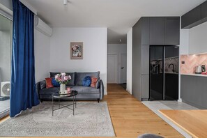 Ein modernes Wohnzimmer mit einem grauen Sofa, einem Couchtisch und einem blauen Vorhang.