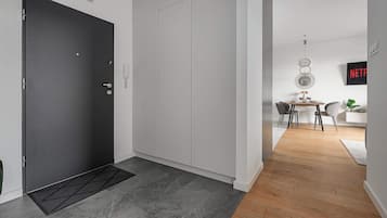 Un interno moderno con una porta scura, un armadio bianco e un'area pranzo con pavimento in legno e tavolo.