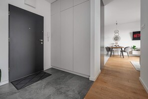Een modern interieur met een donkere deur, een witte kast en een eethoek met een houten vloer en een tafel.