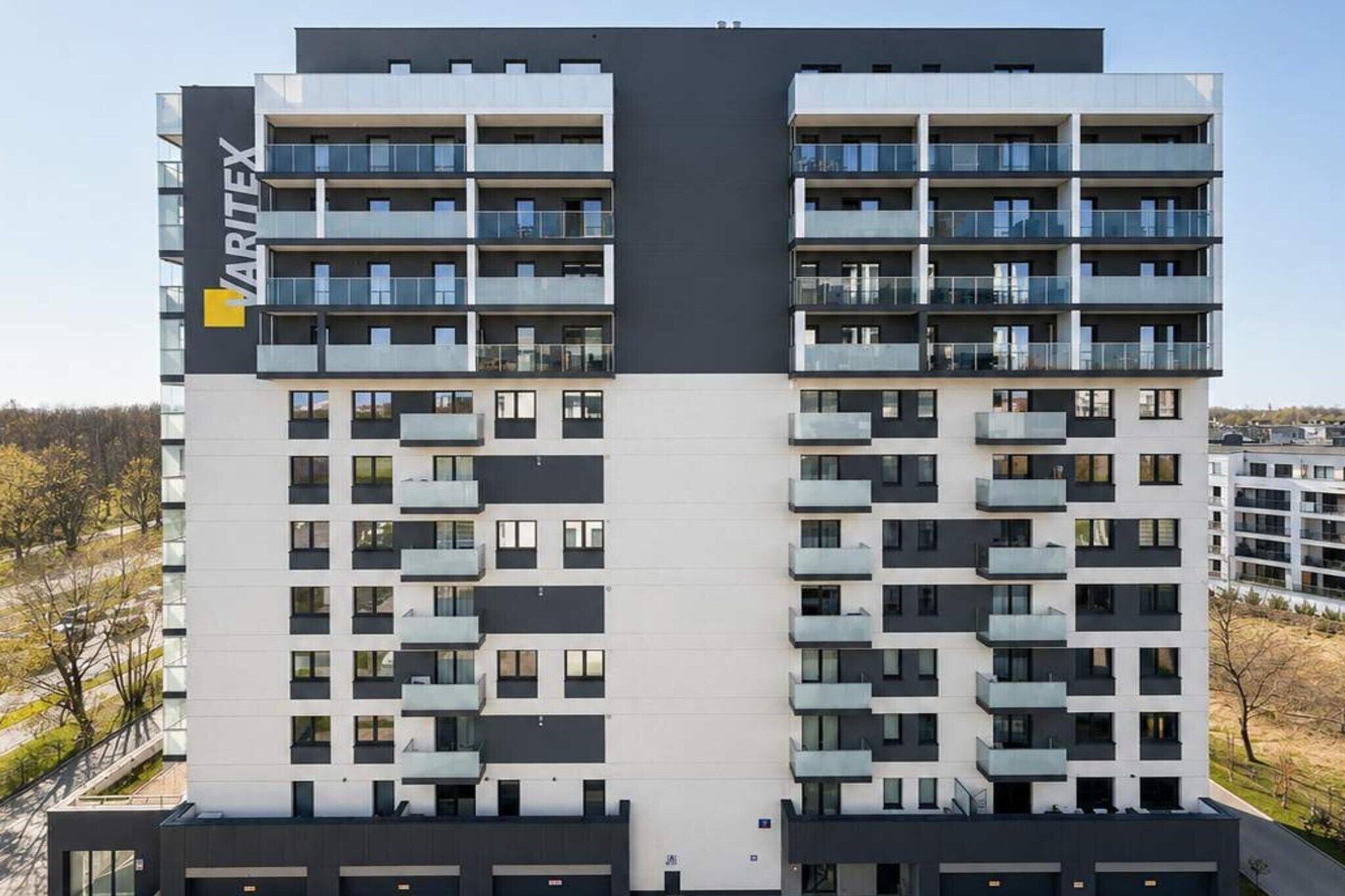 Een meerlaags woongebouw met een modern architectuurontwerp, met balkons op elke verdieping en een opvallend bedrijfslogo op de gevel.