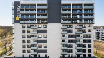 Ein mehrstöckiges Wohngebäude mit moderner Architektur, mit Balkonen auf jeder Etage und einem auffälligen Firmenlogo an der Fassade.