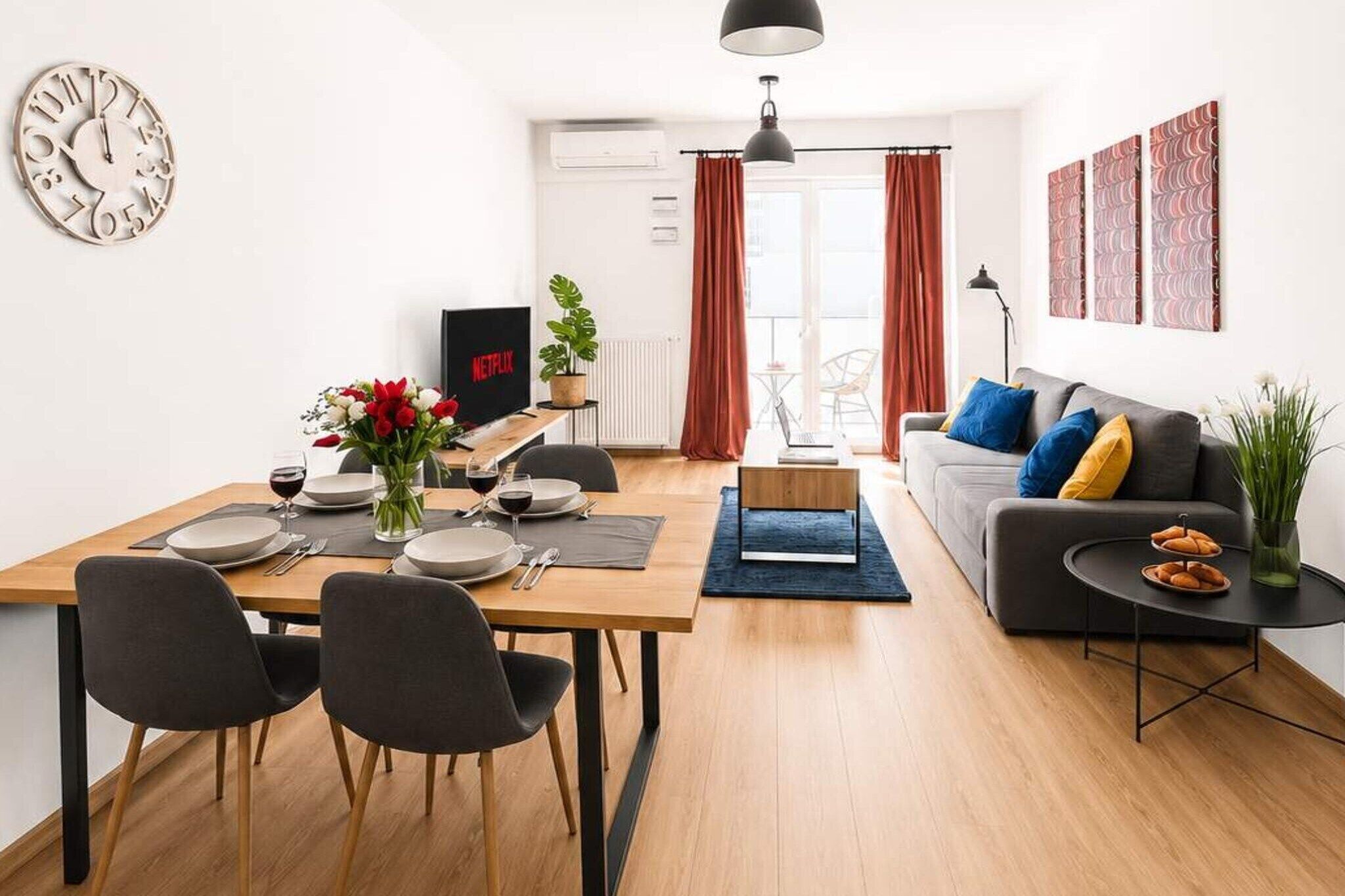 Ein modernes Wohnzimmer mit Essbereich, einer Couch, einem Couchtisch und einem Fernseher.