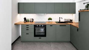 Une cuisine moderne avec des meubles gris, un four noir et un plan de travail en bois.