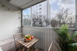 Ein Balkon mit einem Holztisch, einem Korbfruchtkorb und einem Blumentopf.