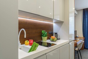 A modern kitchen with a built-in sink, a wooden backsplash, and a countertop with fresh vegetables. - Stylish City Apartment for 3 Guests (Warszawa)