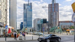 Modernien rakennusten reunustama kaupunginkatu, jossa on jalankulkijoiden suojatie ja raitiovaunu.