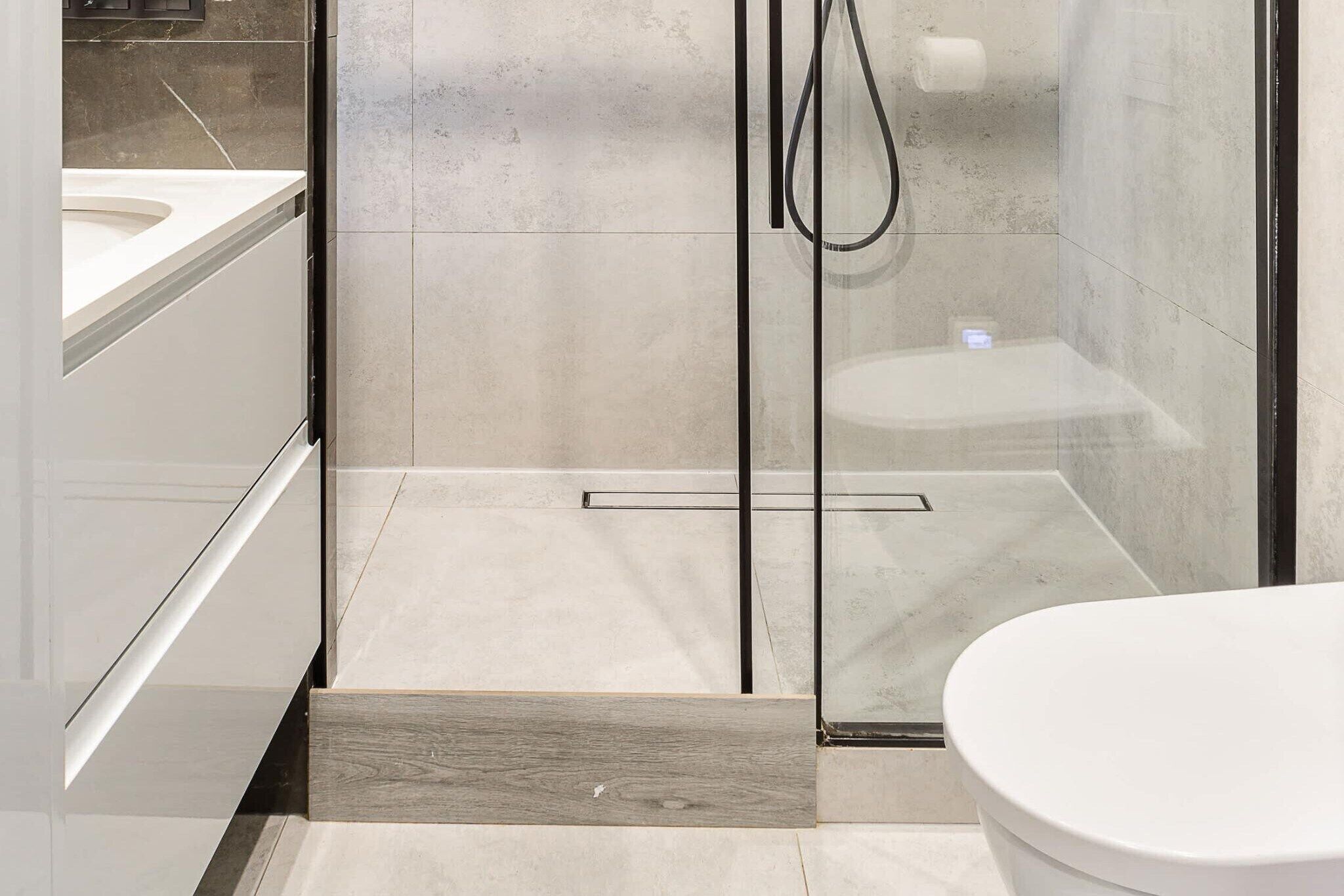 Un baño moderno con ducha de vidrio, inodoro y tocador con espejo.