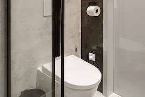 A modern bathroom with a toilet, a paper towel dispenser, and a glass partition. - Stylish City Apartment for 3 Guests (Warszawa)