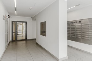 Un couloir avec une porte, une enseigne fixée au mur et un meuble de rangement en métal doté de compartiments numérotés.