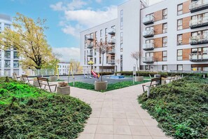 A modern apartment building with balconies, a playground, and a paved walkway. - Cozy Flat near Manufaktura (Łódź)