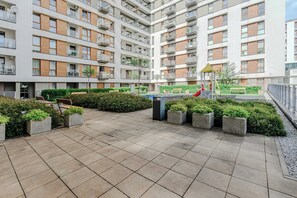 A multi-story residential building with balconies, a playground, and a landscaped courtyard. - Cozy Flat near Manufaktura (Łódź)