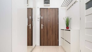 A hallway with two wooden doors, a white cabinet, and a potted plant. - Cozy Flat near Manufaktura ( Łódź)