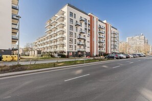 A multi-story residential building with balconies, a parking area with cars, and a clear sky. - Stay near Park & Cafes (Warszawa)
