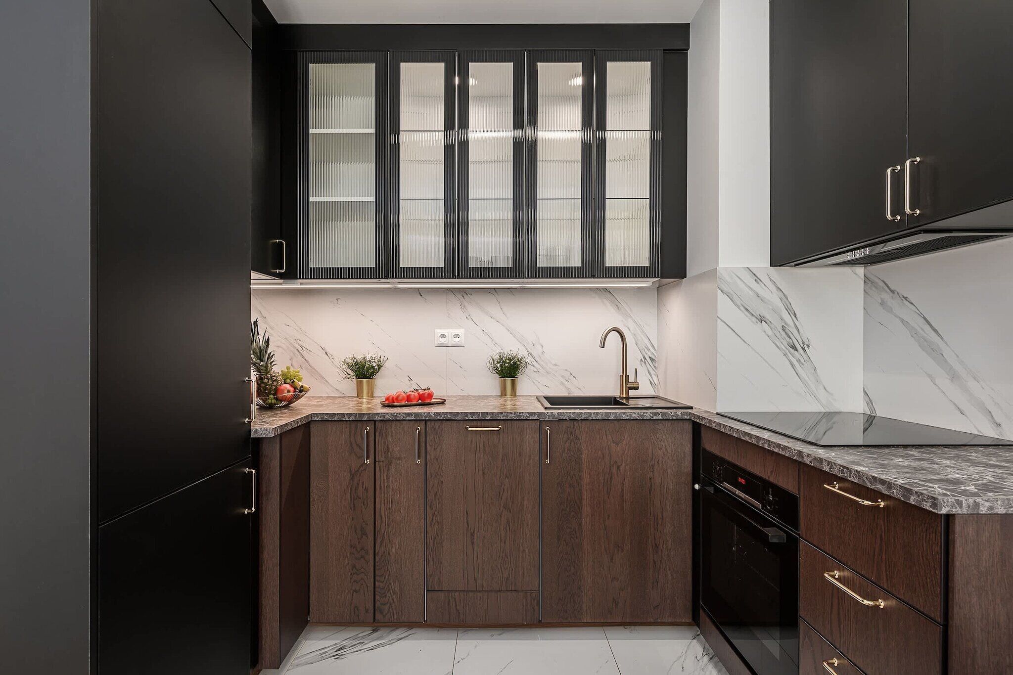 A modern kitchen with dark wood cabinets, a marble countertop, and a built-in oven.