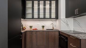 A modern kitchen with dark wood cabinets, a marble countertop, and a built-in oven.