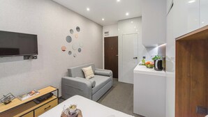 A modern living room with a grey sofa, a flat-screen TV, and a wall decorated with circular mirrors. - Stylish Urban Apartment for 3 (Warszawa)