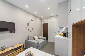 A modern living room with a grey sofa, a flat-screen TV, and a wall decorated with circular mirrors. - Stylish Urban Apartment for 3 (Warszawa)
