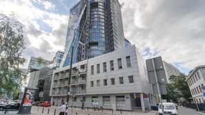 A modern building with a glass facade and a curved structure. - Stylish Urban Apartment for 3 (Warszawa)