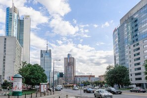 A city street with modern buildings, a tram, and cars. - Stylish Urban Apartment for 3 (Warszawa)