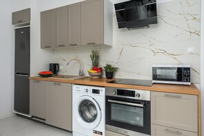 Eine moderne Küche mit eingebauter Waschmaschine, Backofen, Mikrowelle und einem Edelstahl-Kühlschrank.