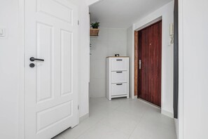 Ein Flur mit einer weißen Tür, einer Holztür und einem weißen Schrank mit Schubladen.
