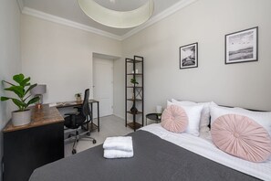 A modern bedroom with a bed, desk, chair, and a plant. - Flat with Quiet Courtyard (Warszawa)