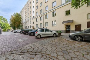 A row of parked cars along a cobblestone street in front of a multi-story building with windows and a door. - Flat with Quiet Courtyard (Warszawa)