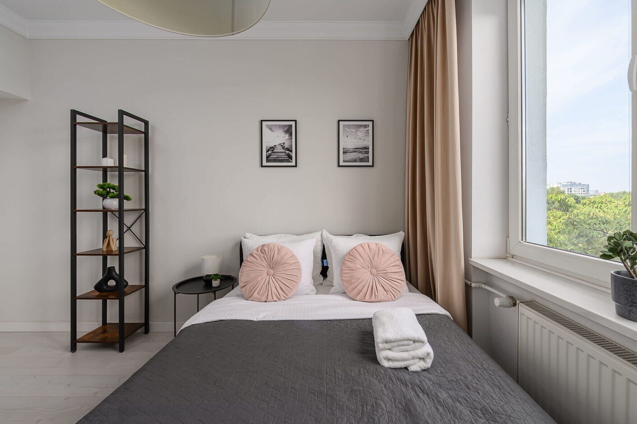A bedroom with a bed, a nightstand, a bookshelf, and a window with curtains.