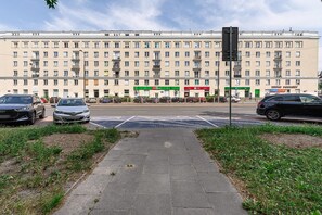 A multi-story building with a row of shops on the ground floor, including a pharmacy and a bank. - Flat with Quiet Courtyard (Warszawa)