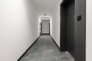 A long, narrow hallway with a dark floor and light walls, leading to a door at the end. - Charming House in Landéda with Sea View (Łódź)