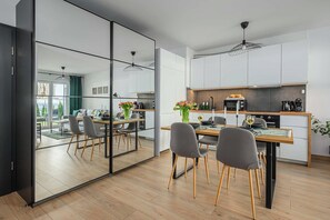 A modern kitchen with a dining area, a large mirror, and a view of the living room. - Ground-Floor Apartment Stay with Garden Terrace (Łódź)