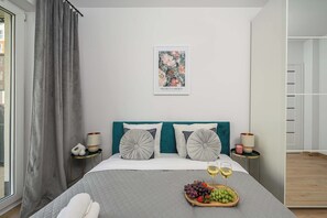 A bedroom with a bed, a framed artwork, bedside tables with lamps, and a fruit basket with glasses. - Ground-Floor Apartment Stay with Garden Terrace (Łódź)