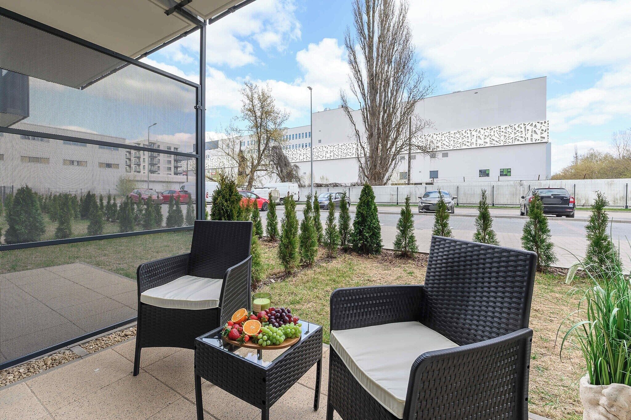 An outdoor seating area with wicker chairs and a table set with fruit.
