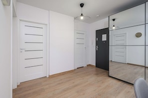 A room with a wooden floor, white walls, a large mirror, and a black door. - Ground-Floor Apartment Stay with Garden Terrace (Łódź)