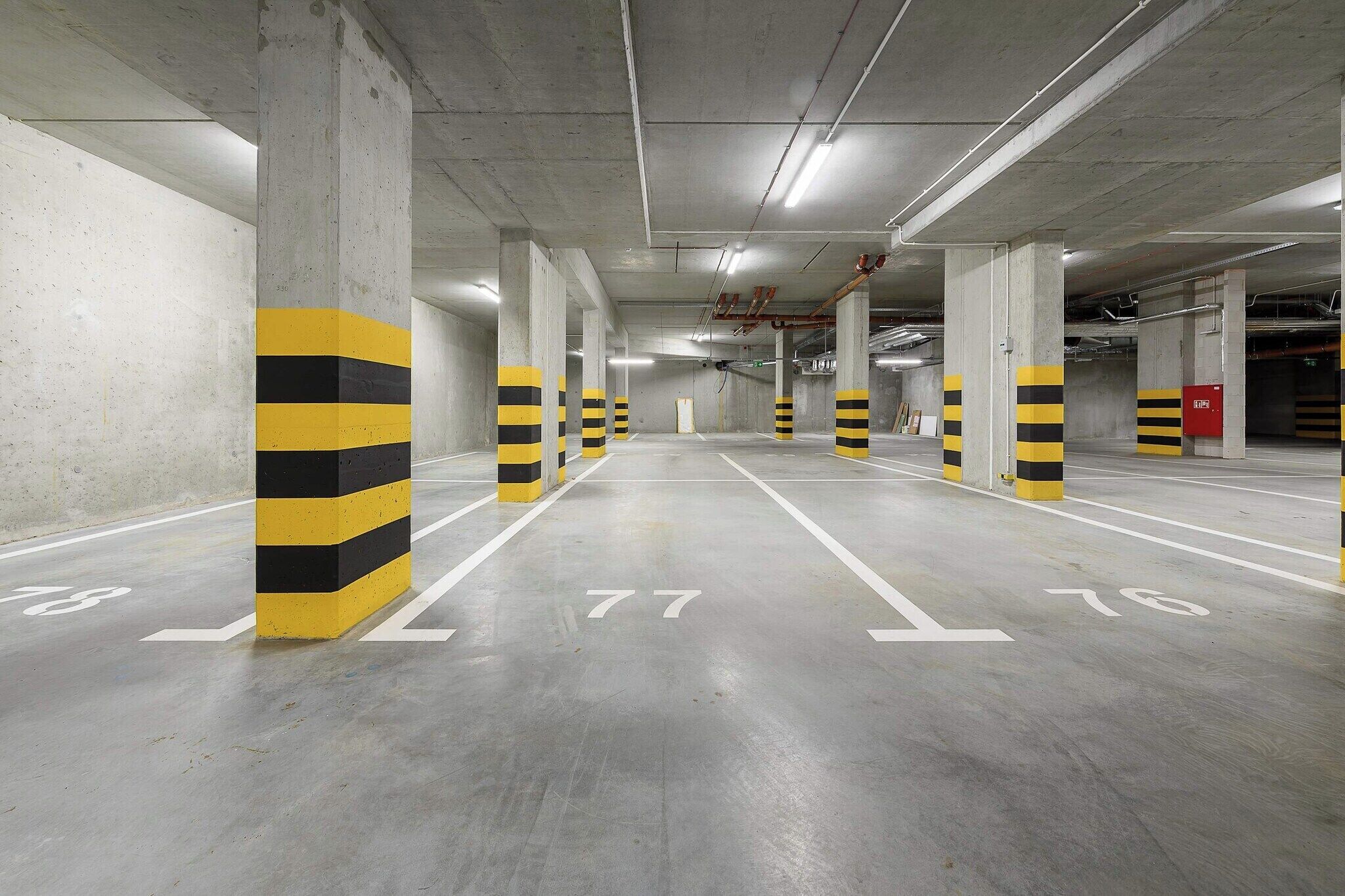 Een parkeergarage met meerdere niveaus, betonpilaren en witte parkeerlijnen.