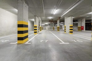 A multi-level parking garage with concrete pillars and white parking lines. - Ground-Floor Apartment Stay with Garden Terrace (Łódź)