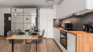 Een moderne keuken met een houten aanrecht, een ingebouwde oven en een eethoek met een tafel gedekt voor twee personen.