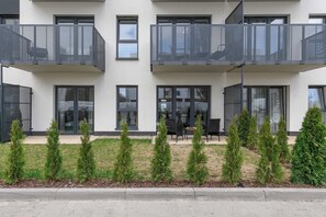 A modern building with multiple balconies, large windows, and a landscaped area with small trees. - Charming House in Landéda with Sea View (Łódź)
