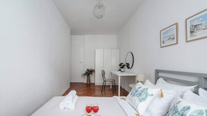 Ett hotellrum med en säng, ett skrivbord, en stol, en spegel och utsikt över stranden.